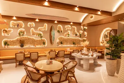 Rattan chairs around pale round tables against the sculpted wall at City Centre Mirdif