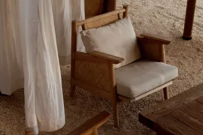 A cane and timber armchair with a linen cushion on the garden terrace at Under The Tree, Diriyah