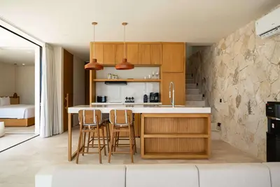 A timber kitchen island and stools against a stone wall at Ohana Villa