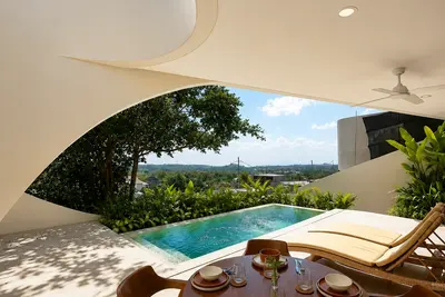 A round timber dining table and chairs beside the pool at Villa Sunseeker