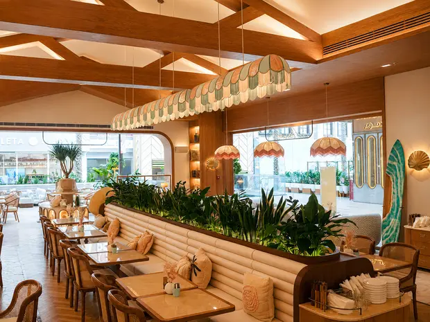 A timber coffered ceiling above banquette seating and planting at Aurora, Kuwait City
