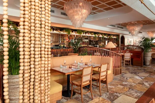 Timber chairs and banquettes seen through a beaded curtain at Canary Club, Jumeirah Lakes Towers